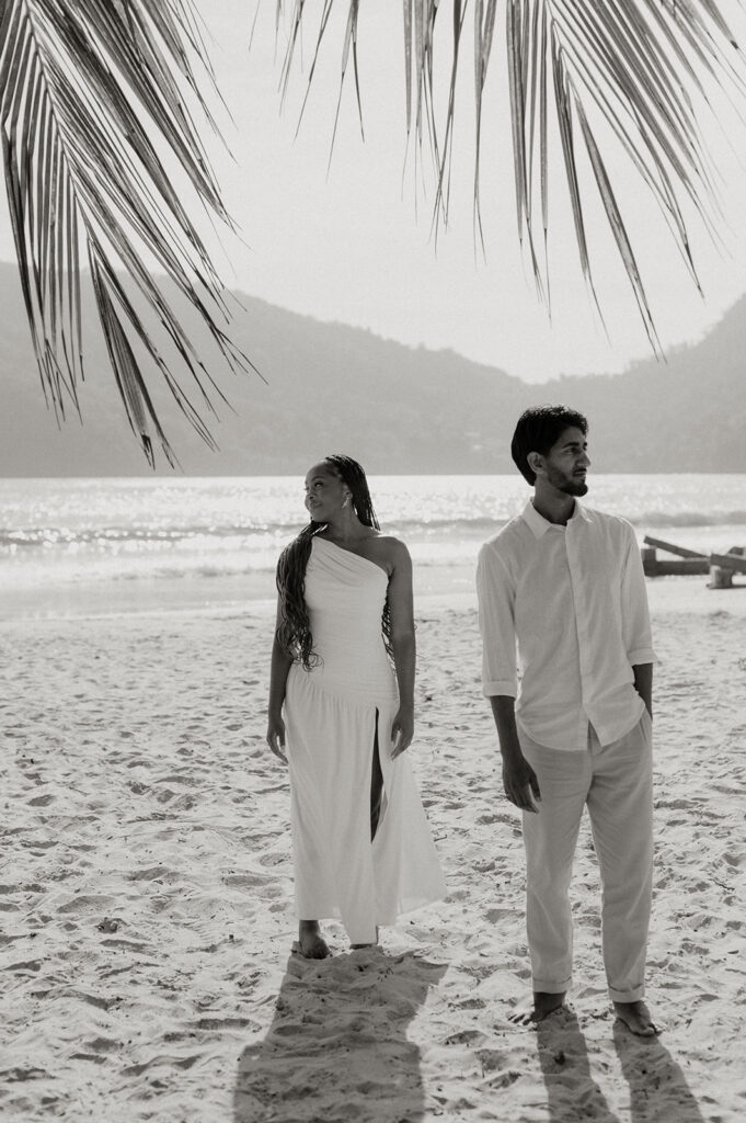 Candid photo of the couple embracing by the ocean with soft golden sunlight around them
