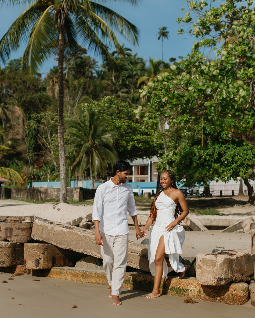 Candid photo of the couple embracing by the ocean with soft golden sunlight around them
