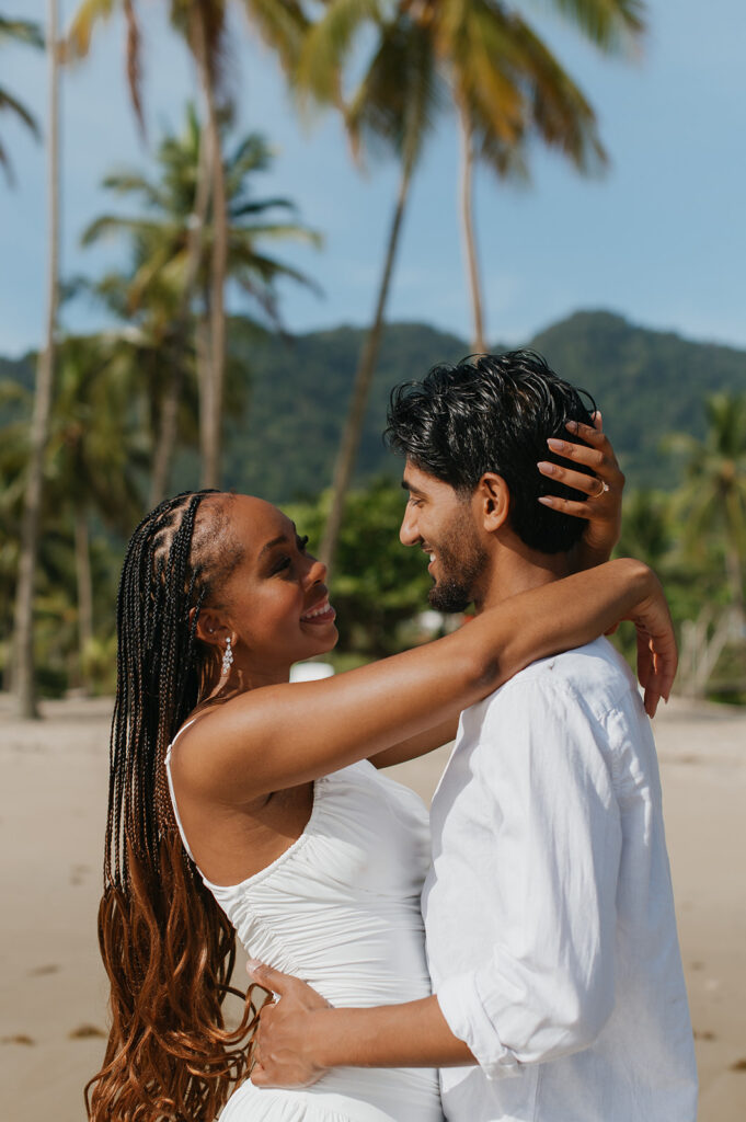 A couple walking hand in hand along the shoreline at Maracas Beach during their engagement session
