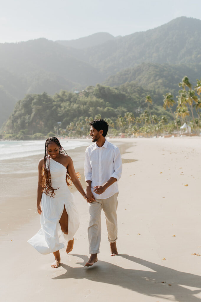 Brandon and Qetsia laughing together in the sand with palm trees in the background
