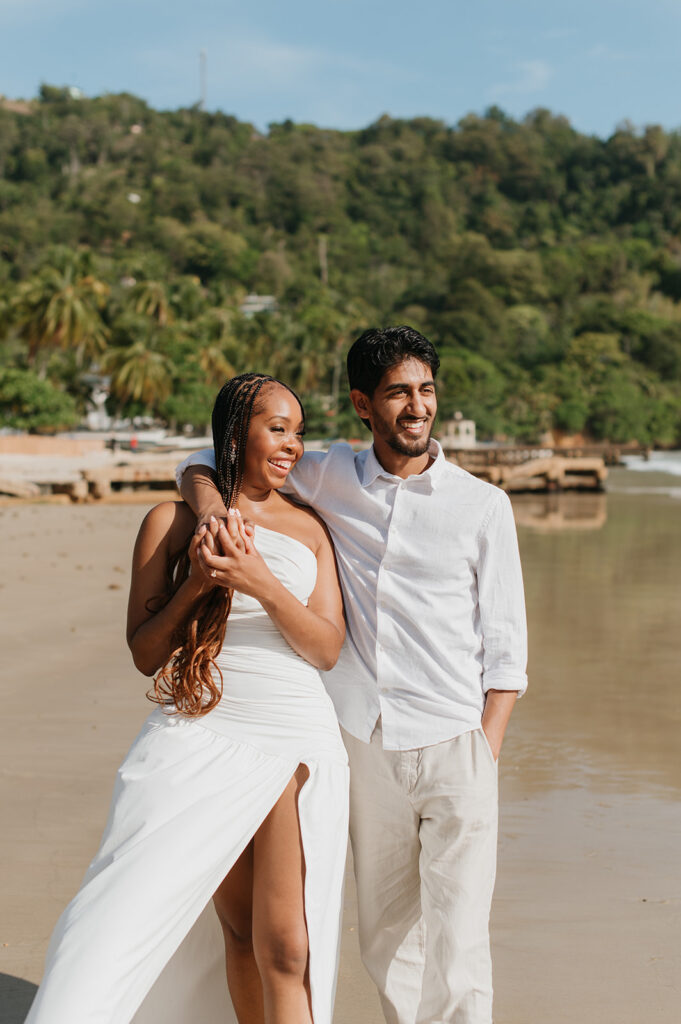 Brandon and Qetsia laughing together in the sand with palm trees in the background
