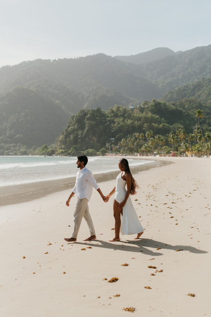 Brandon and Qetsia laughing together in the sand with palm trees in the background
