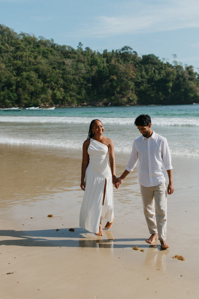 Brandon and Qetsia laughing together in the sand with palm trees in the background
