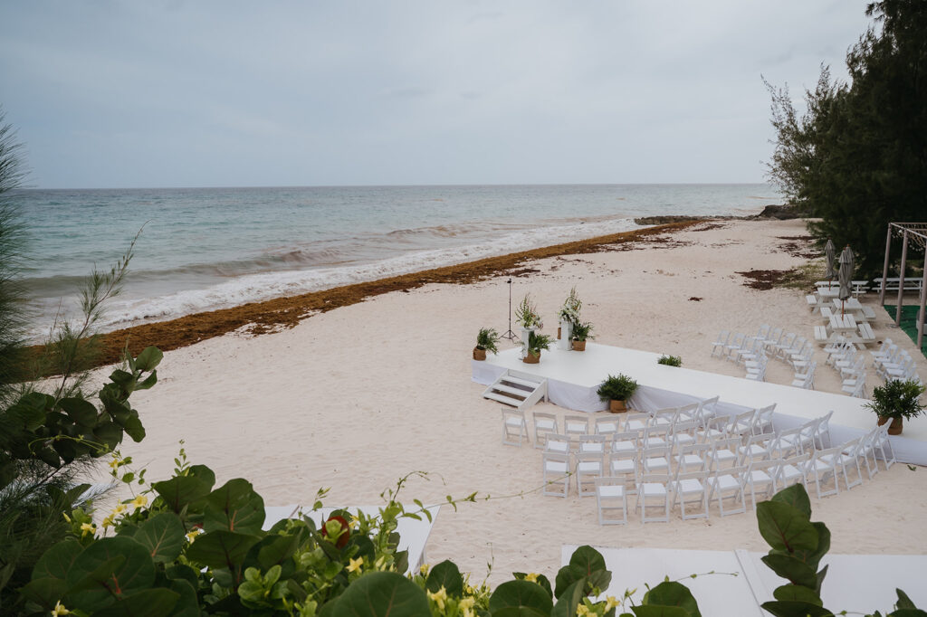 Wedding ceremony setup on the beach with tropical floral decor and ocean views
