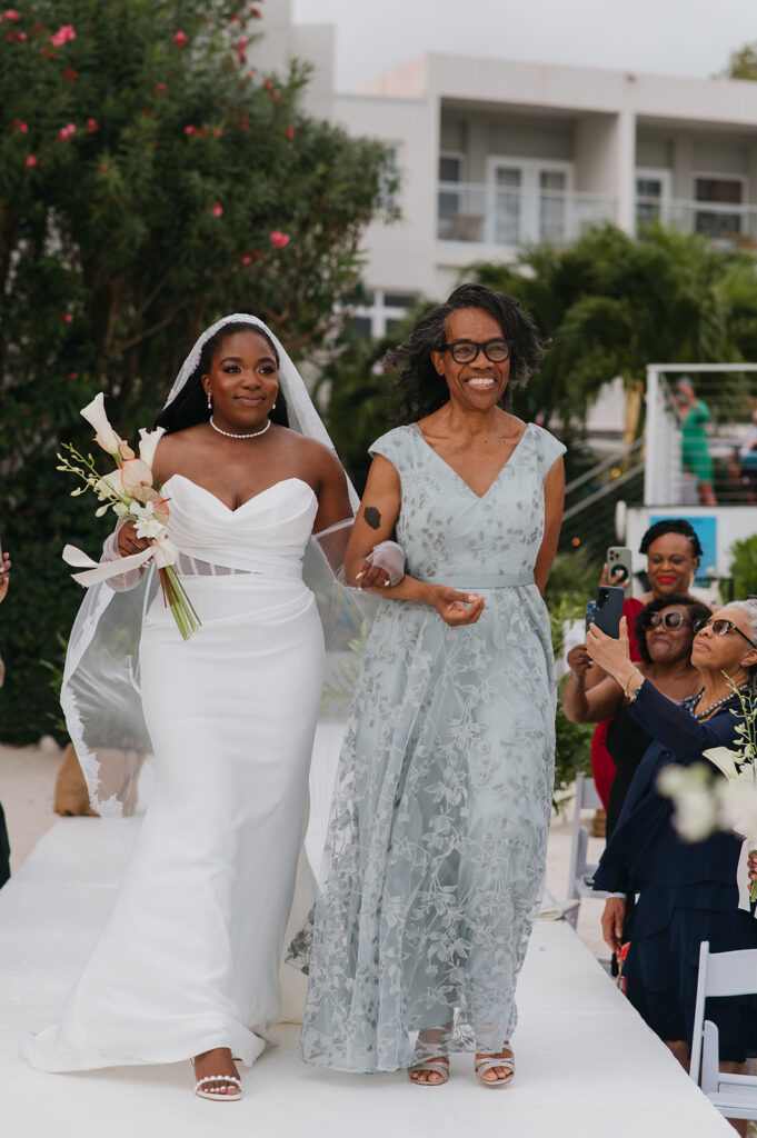 Wedding ceremony setup on the beach with tropical floral decor and ocean views
