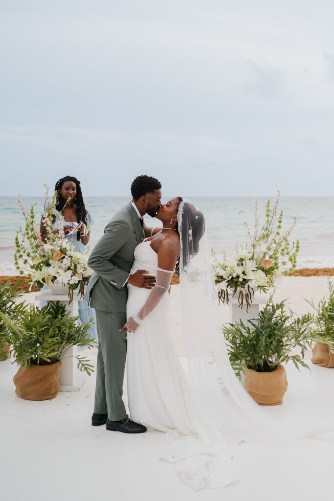 Wedding ceremony setup on the beach with tropical floral decor and ocean views
