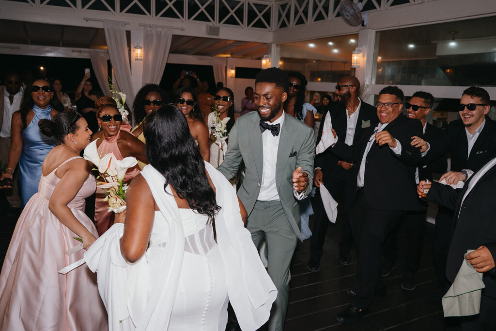 Bride and groom dancing at their beachfront reception under string lights
