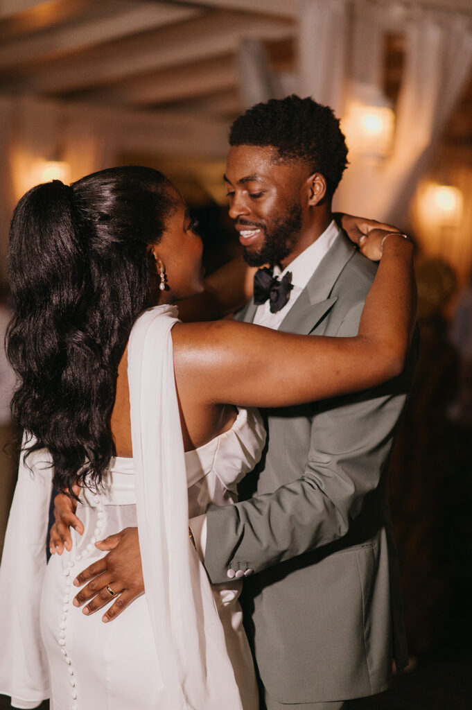 Bride and groom dancing at their beachfront reception under string lights

