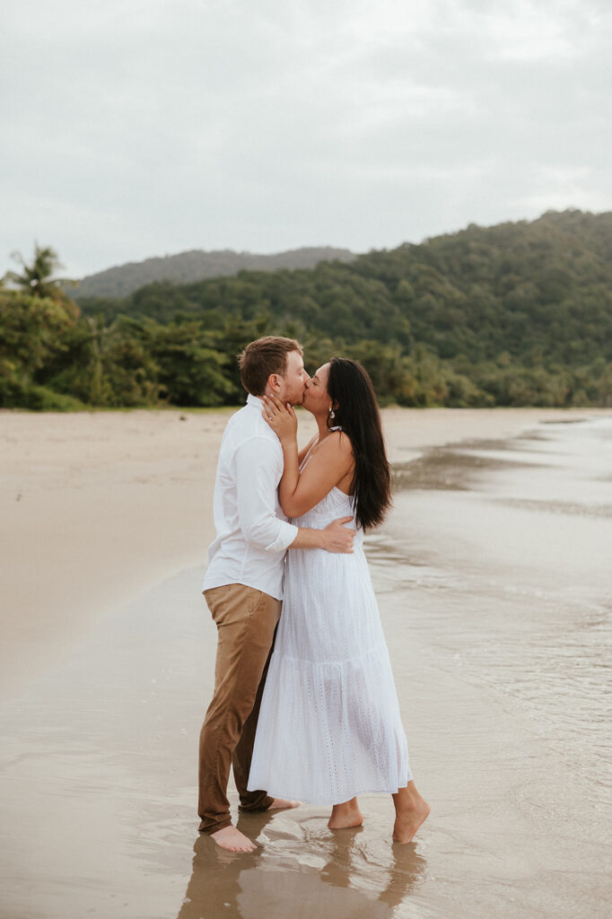 Playful engagement moment as Ross twirls Andrea in the empty stretch of beach during golden hour.

