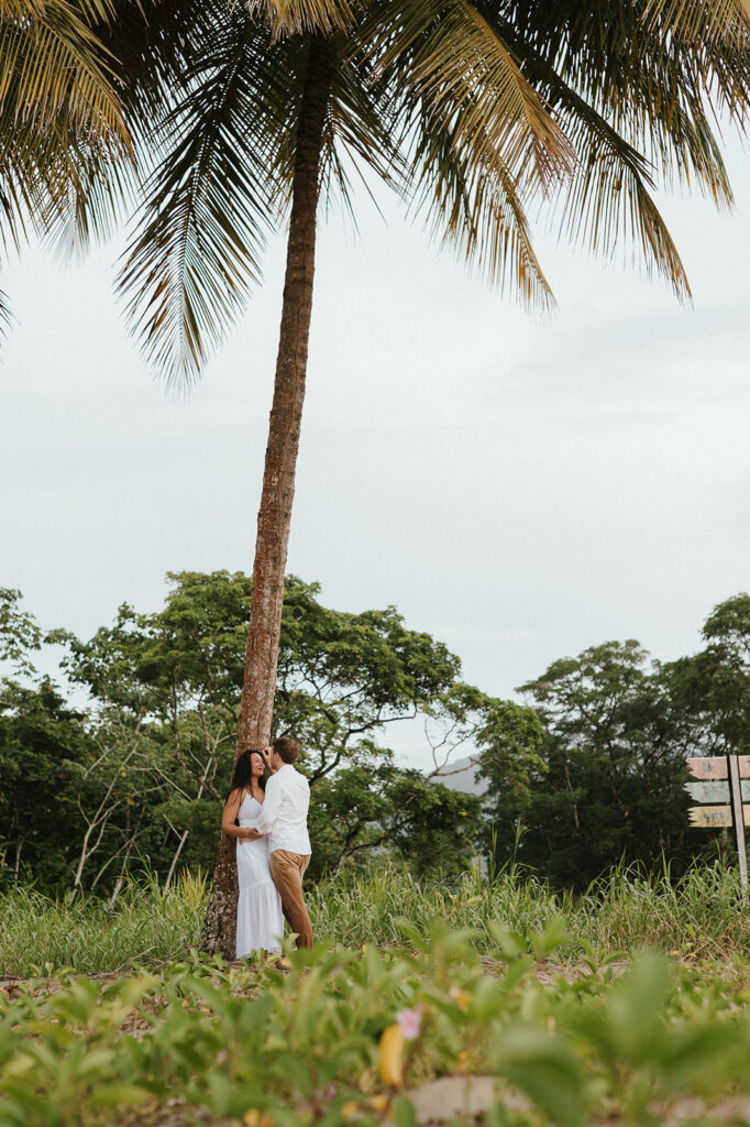 Newly engaged couple laughing during a celebration on the sand at Las Cuevas Beach.
