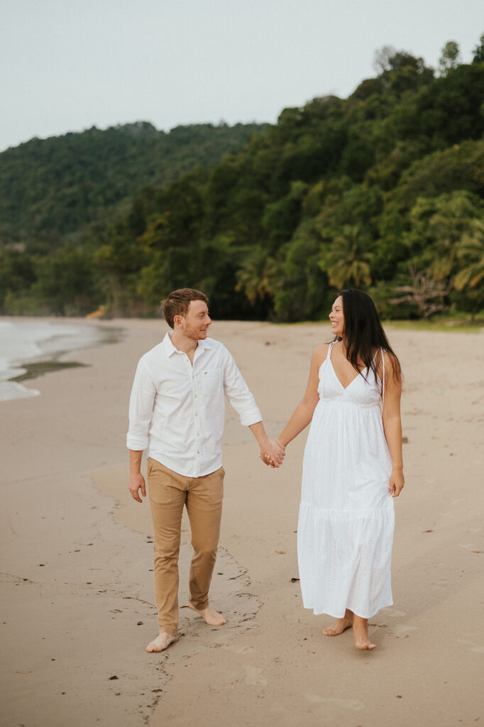 Playful engagement moment as Ross twirls Andrea in the empty stretch of beach during golden hour.
