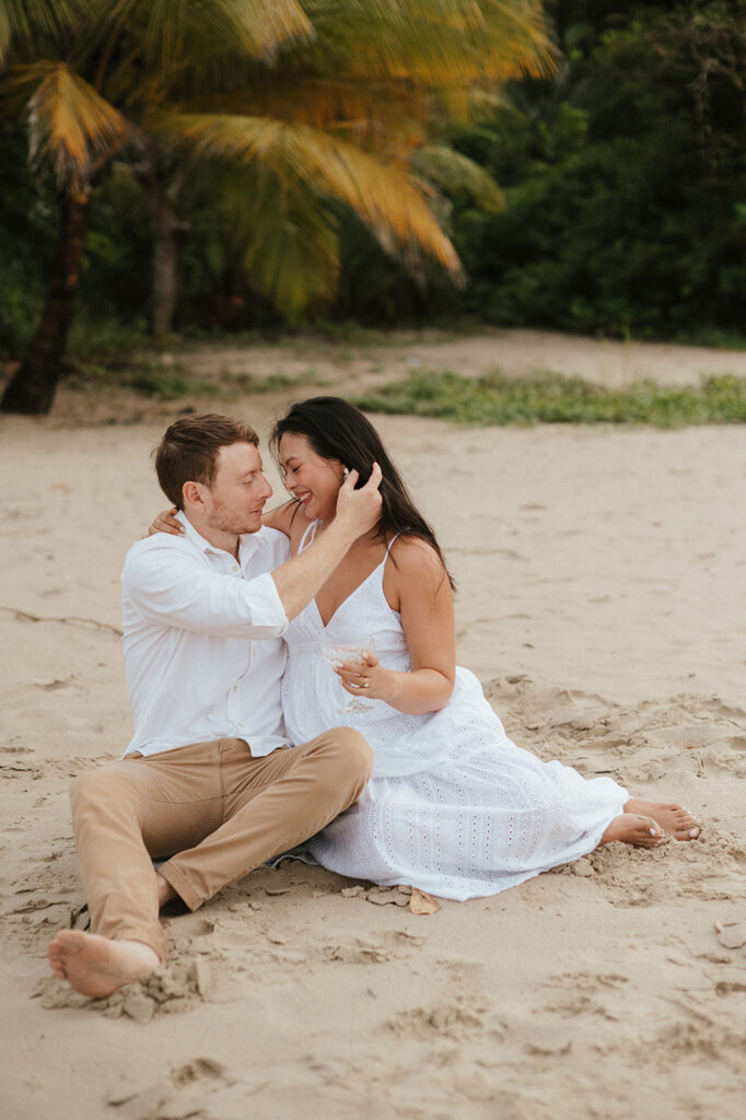 Andrea and Ross holding hands while walking barefoot along the shoreline with soft waves behind them.
