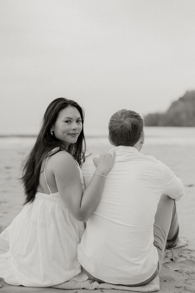 Couple embracing and smiling with the cliffs and ocean views of Las Cuevas Beach in the background.
