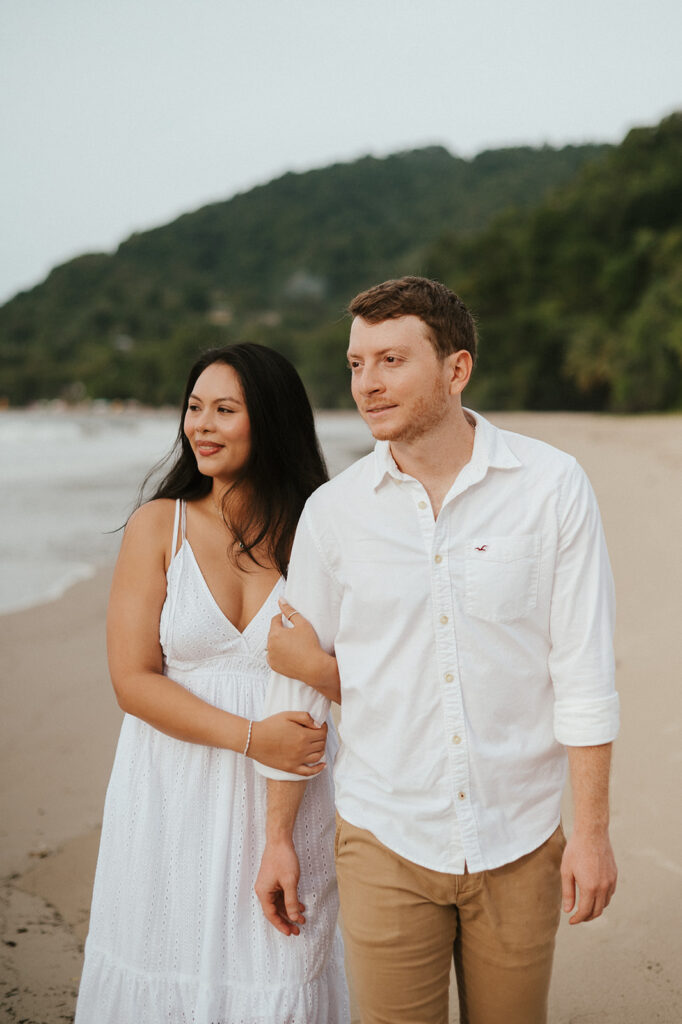 Couple embracing and smiling with the cliffs and ocean views of Las Cuevas Beach in the background.
