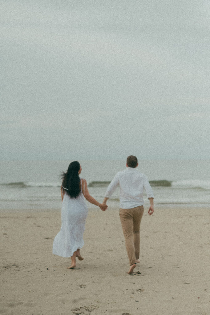 Couple embracing and smiling with the cliffs and ocean views of Las Cuevas Beach in the background.
