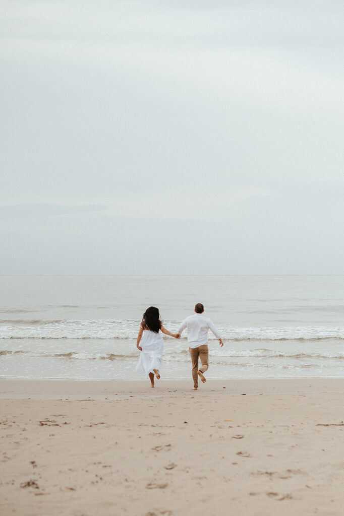 Couple embracing and smiling with the cliffs and ocean views of Las Cuevas Beach in the background.
