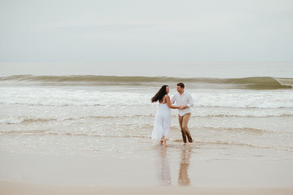 Couple embracing and smiling with the cliffs and ocean views of Las Cuevas Beach in the background.

