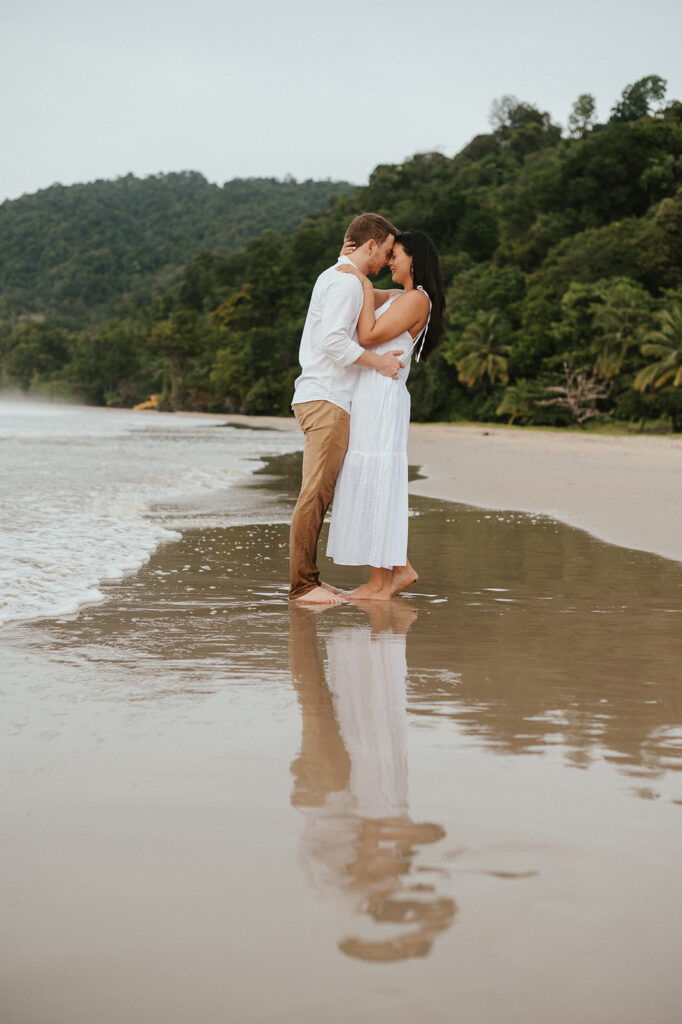 Playful engagement moment as Ross twirls Andrea in the empty stretch of beach during golden hour.
